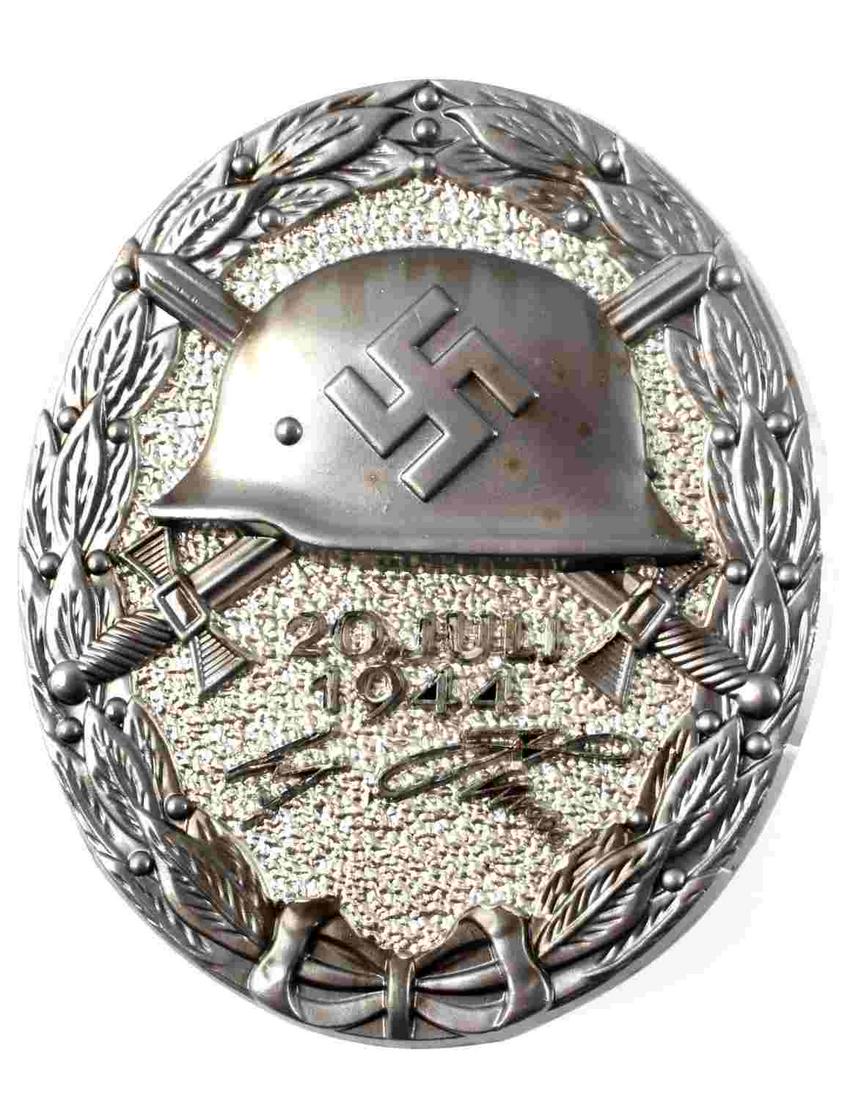 WWII GERMAN BLACK ADOLF HITLER 1944 WOUND BADGE: German WWII Black Adolf Hitler July 20, 1944 Wound Badge. Measures 1 3/8” wide 1 11/16” tall. The front shows a German helmet in the center with a pair of crossed swords in the back ground. Below 