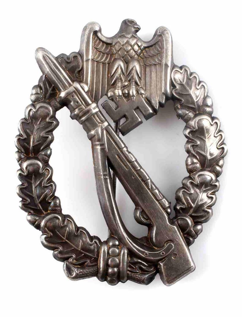 WWII GERMAN ARMY SILVER INFANTRY ASSAULT BADGE: WWII German Army Silver Infantry Assault Badge. The front has a Mauser K-98 rifle in the center with an army eagle clutching a swastika in his talons at the top. Both are surrounded by an oval oak lea