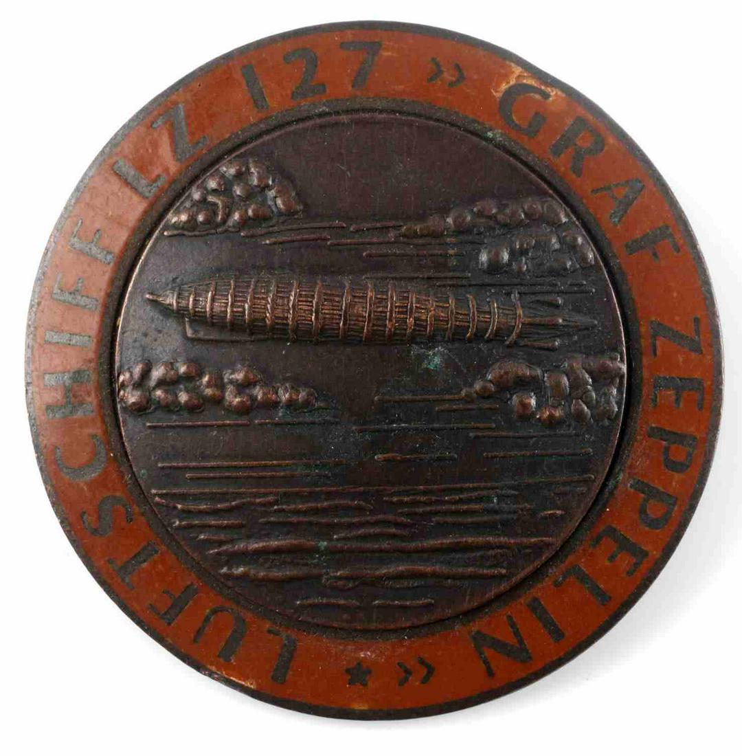 WWII GERMAN THIRD REICH LZ 127 ZEPPEPLIN AIR BADGE: German WWII LZ 127 Graf Zeppelin Luftschiff Air Ship Badge. Measures 1 3/4" in diameter. The front reads ‘LZ 127 Graf Zeppelin Luftschiff’. It shows the Zeppelin flying over the ocean in the cente