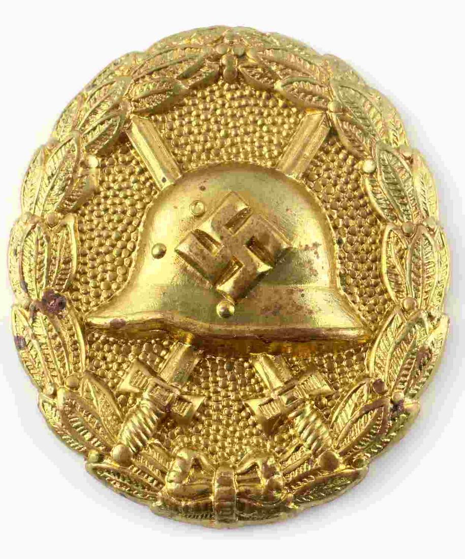 WWII THIRD REICH GOLD CONDOR LEGION WOUND BADGE: German World War II Gold Condor Legion Wound Badge. The front shows a German helmet in the center with a pair of crossed swords in the back ground. All three are surrounded by an oval oak leaf wreath.