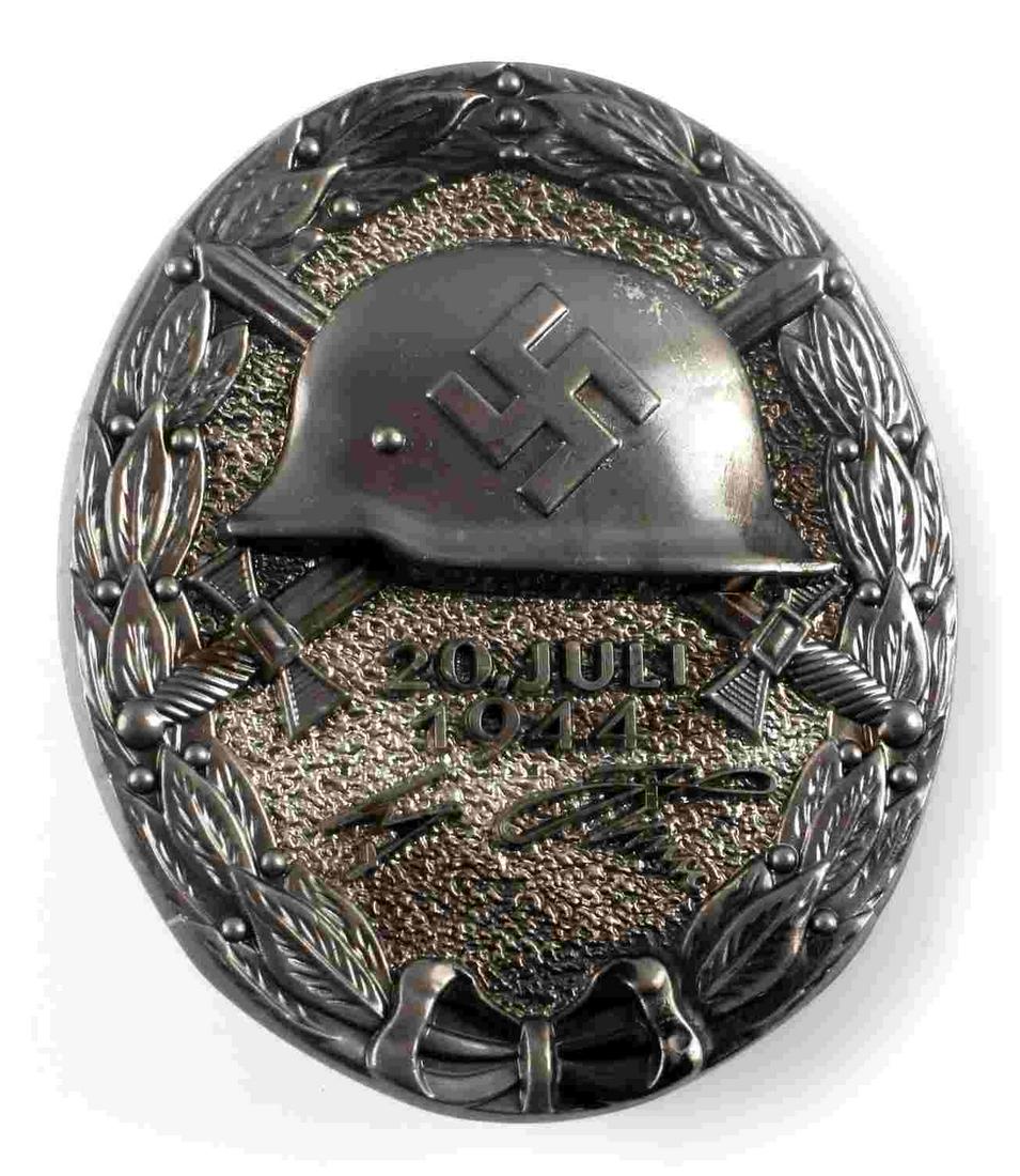 WWII GERMAN 1944 BLACK ADOLF HITLER WOUND BADGE: German WWII Black Adolf Hitler July 20, 1944 Wound Badge. Measures 1 3/8” wide 1 11/16” tall. The front shows a German helmet in the center with a pair of crossed swords in the back ground. Below 
