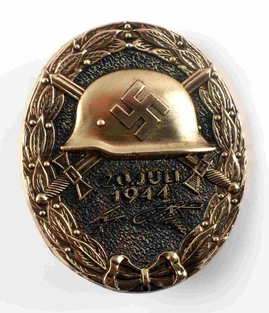 WWII GERMAN GOLD ADOLF HITLER 1944 WOUND BADGE: German WWII Gold Adolf Hitler July 20, 1944 Wound Badge. Measures 1 3/8” wide 1 11/16” tall. The front shows a German helmet in the center with a pair of crossed swords in the back ground. Below r