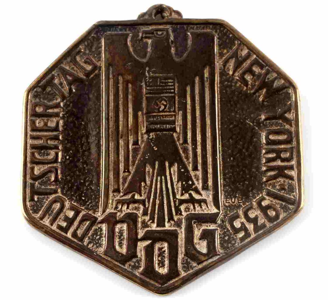 GERMAN AMERICAN BUND WWII 1935 DEUTSCHER MEDAL: German American Bund WWII 1935 Deutscher Tag New York VDG Medal Decoration. Measures 1 5/16” wide by 1 9/16” tall. The front shows a German World War II eagle with a swastika in the center of his 