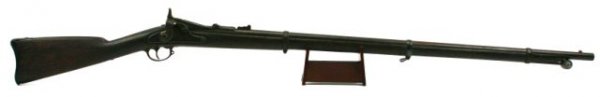 US SPRINGFIELD 1865 MODEL TRAPDOOR RIFLE: 36 inch round barrel. Lock marked "Springfield" and "1865". Metalwork is toned overall with minor pitting, especially to parts of the barrel. The stock is heavily used with some carved lettering to th
