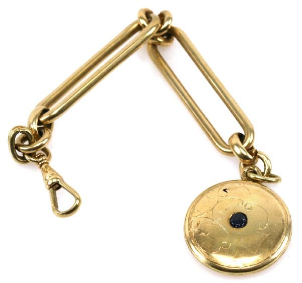 14K GOLD WATCH FOB W/ LOCKET: Unusual 14K yellow gold pocket watch FOB with locket. The FOB is 5 inches long and the locket is 1 inch in length. Blue stone set into locket. Weighing 24.7 grams. Circa 1920s.
