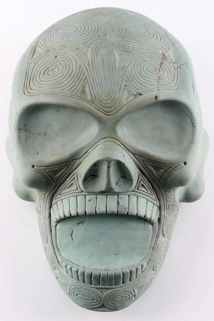 PRE COLUMBIAN TAINO MASSIVE SKELETAL HEAD W TEETH: Massive skeletal head with prominent teeth. Made from a blueish stone similar to jasper, found in the Dominican Republic. An obvious female symbol at center of the head and the number of swirl bird he