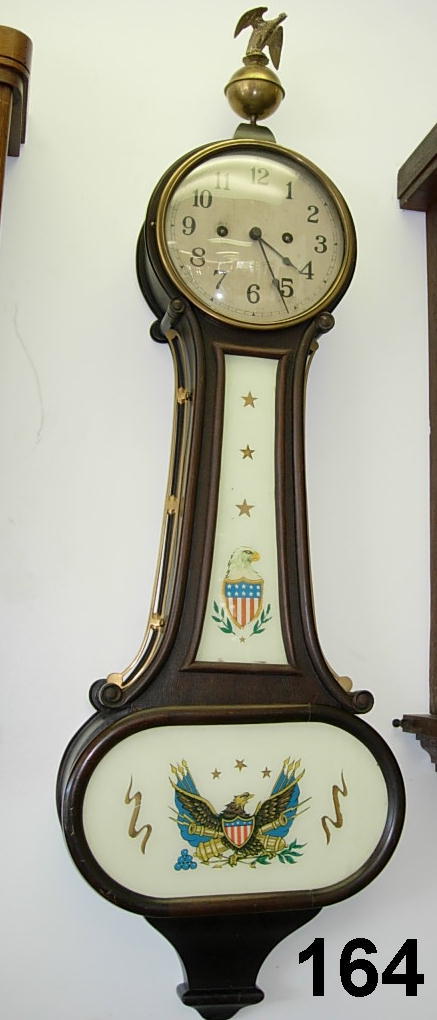 ANTIQUE BANJO WALL CLOCK NEW HAVEN CON EAGLE: C.1900 BANJO WALL CLOCK, NEW HAVEN, CONN. MAHOGANY BRASS MOVEMENT, HEAVY SILVERED METAL DIAL, REVERSED PAINTED THROAT AND BASE PANELS OF EAGLE AND SHIELD, LARGE BRASS OPEN WINGED PHOENIX BIRD ON BALL