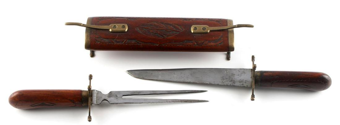 INDIAN MEAT CARVING KNIFE SET IN WOODEN CASE: One (1) meat carving knife set with knife and fork and wooden holding case. Wooden grips and case with brass fittings. Wooden has a carved design. Both fork and knife blade marked "INDIA". Knife handl