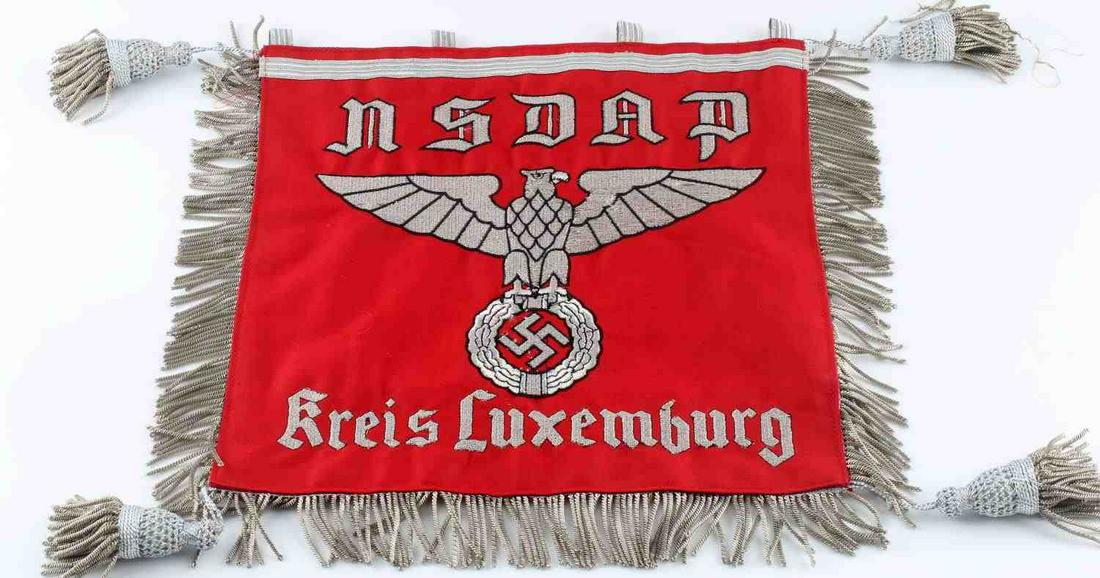 WWII GERMAN NSDAP KREIS LUXEMBURG CAR PENNANT: Red cotton with silver fringe and tassels, party title and eagle to one side and swastika to other, measures 12 X 12 inches. Very good condition. Does fluoresce under blacklight at border seam and thr