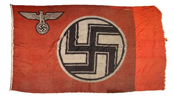 THIRD REICH CAPTURED FLAG FROM BERLIN: THIRD REICH CAPTURED FLAG FROM BERLIN Large printed flag of 12 x 7.5 feet. Reputedly shot from a flag pole in Berlin by a US Veteran. Stained overall and with some old repairs and additions. Hang hook