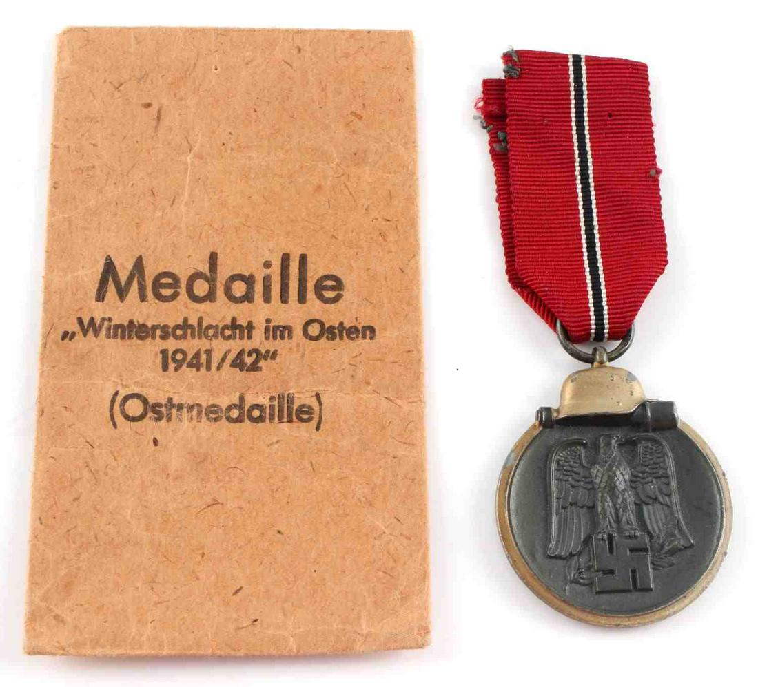WWII GERMAN EASTERN FRONT MEDAL WITH RIBBON: WWII German Eastern Front medal with ribbon and presentation envelope. Obverse: Reichsadler to center with helmet and telescope above. Gunmetal color with a brighter gilded color around the edge. Reve