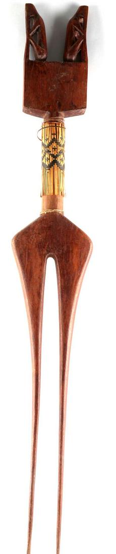 PACIFIC ISLANDER DOUBLE PRONG WOOD STATUE: A double prong wooden statue from Pacific Islands. Has two people atop the statue in a hunched over grieving position. Handle is wrapped with string and wooden strips. Strips have a black motif drawn 