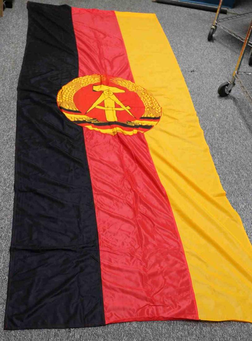 GERMAN DEMOCRATIC REPUBLIC FLAG EAST GERMANY: Adopted in 1959. Tricolor: black, red, yellow, with East German Coat of Arms: compass and hammer encircled with rye. Measures 112 X 43 inches. Good condition.
