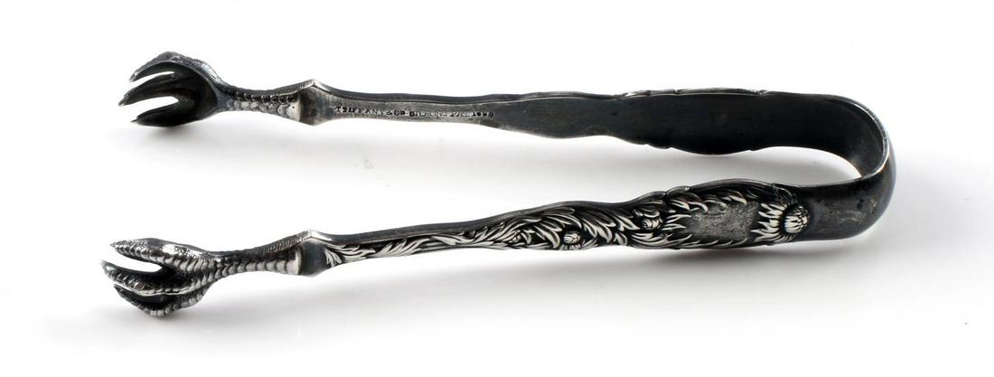 TIFFANY & CO. STERLING SILVER ANTIQUE SUGAR TONGS: Hallmarked Tiffany & Co. Sterling Pat 1880. Monogrammed MM, high relief sunflower and claw motif. Total weight 29.6 grams, length 4 1/2 inches. In good condition.. Size: RM SAFE This lot has a reserve
