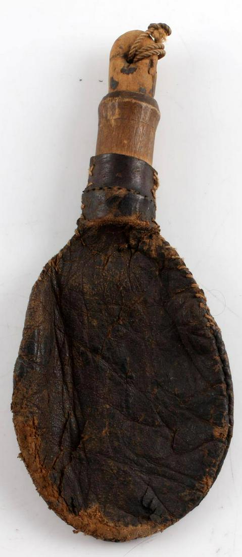 ANTIQUE REVOLUTIONARY WAR ERA LEATHER SHOT FLASK: Revolutionary War era leather shot flask with wooden stopper. Measures approximately 6 inches long and 2.5 inches wide. The shot flask is in a riker mount that measures 6.5 X 8.5 inches. Very good, or