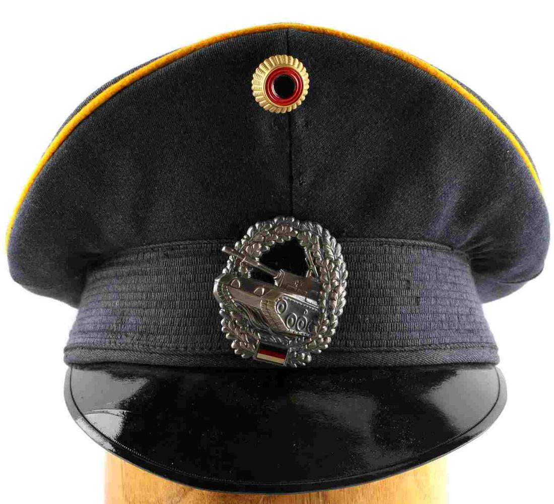 POST WAR WEST GERMAN PEAKED VISOR PANZER DIVISION: Blue wool cap with yellow piping, bullseye at top center, West German tank badge at center, maker label to inside, size 54. Very good condition.