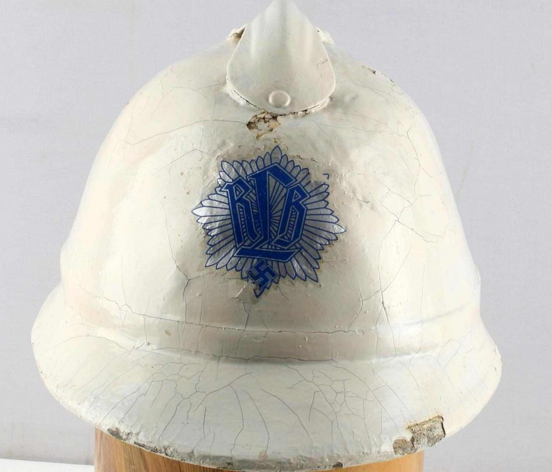 FRENCH ADRIAN HELMET REPURPOSED FOR GERMAN RLB: Painted white with RLB emblem and swastika to front center. Elastic cloth liner and leather sweatband. Worn leather chinstrap. Heavy crazing of paint. Overall fair condition. Measures 7 7/8 inches fro