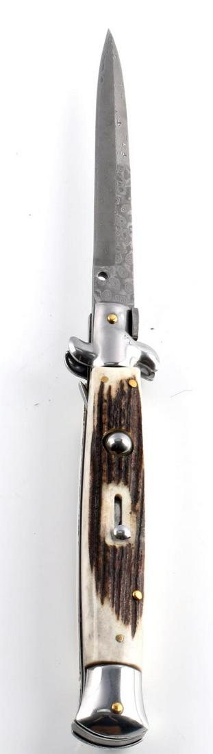 AKC ITALIAN SWING GUARD STILETTO SWITCHBLADE KNIFE: AKC Italian swing guard stiletto switchblade knife. "AKC Italy" stamped on the blade. Features a stag handle with a Damascus-style blade and a locking mechanism. Measures 11 inches open, 6.5 inches cl