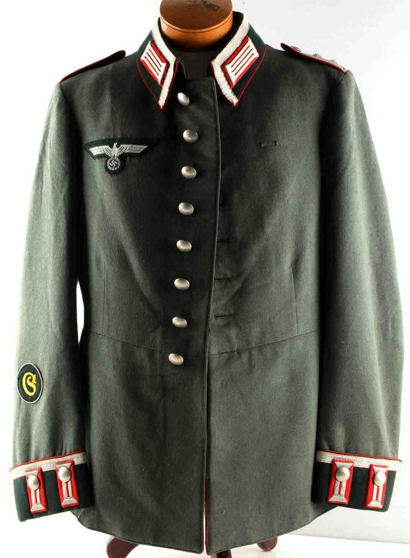 WWII GERMAN THIRD REICH ARTILLERY OFFICER TUNIC: Third Reich artillery tunic. Silver embroidery with red piping. Collar tabs and shoulder boards of first sergeant rank. Interior pocket with tag "Emil Kraft & Cie., GRAZ. Named, numbered, and a dated 