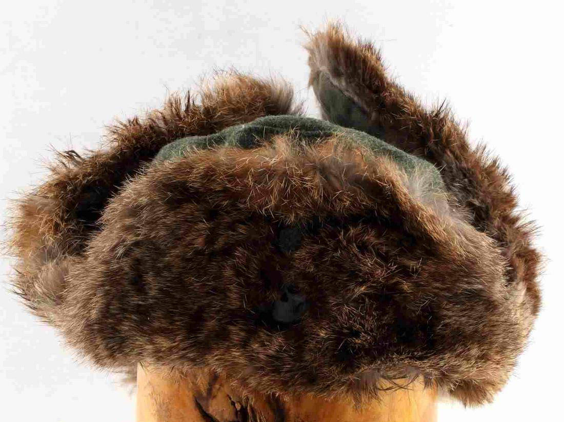 WWII THIRD REICH WAFFEN SS RUSSIAN FRONT HAT: WWII Third Reich Russian rabbit fur front hat. Green fabric underneath rabbit fur and inner lining. Has Totenkopf and Parteiadler. Inside marked with writing, including "1941." Size 57. Does not fluor