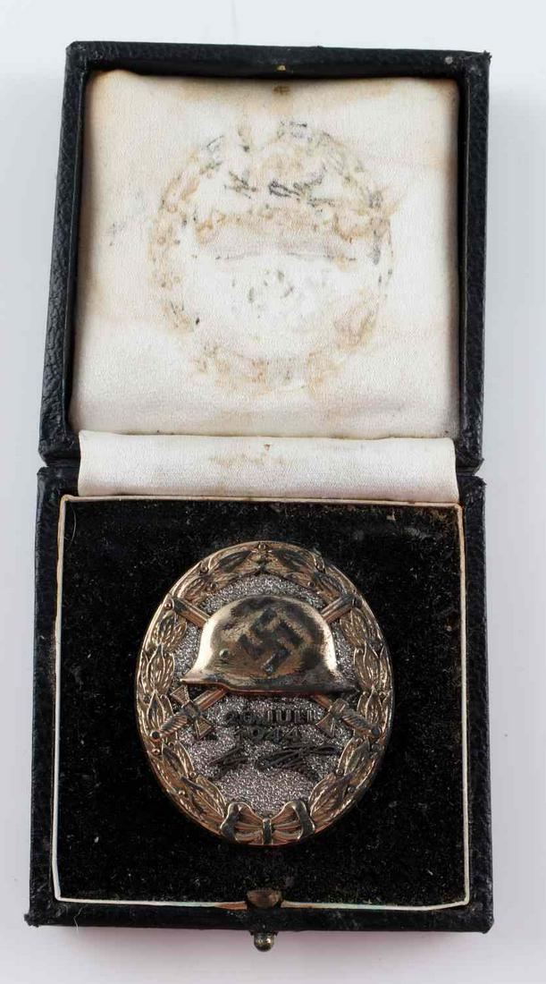 CASED WWII GERMAN JULY 20 1944 GOLD WOUND BADGE: Cased WWII German gold Adolf Hitler July 20, 1944 wound badge. Awarded to the survivors of the attempted bombing of the Wolf's Lair. Obverse features a German helmet with swastika to center with a pai