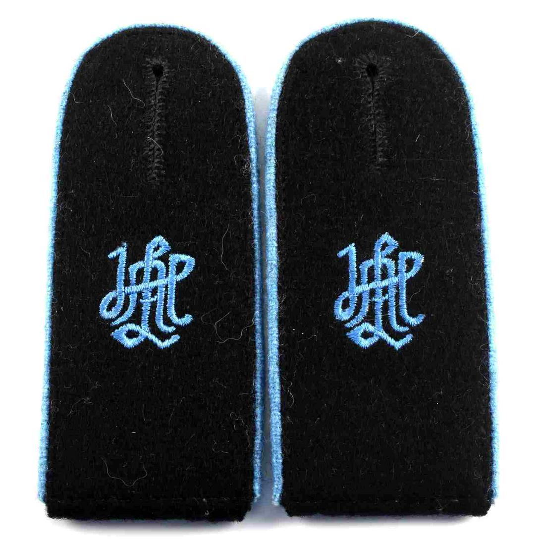 2 WWII GERMAN WAFFEN SS LAH EM SHOULDER BOARDS: Machine embroidered ‘LAH’ Leibstandarte Adolf Hitler cypher in the center of a black wool backing. Light blue piping. Measures 1 7/8 X 8 1/4 inches. Multi piece machine sewn wool and cotton constr