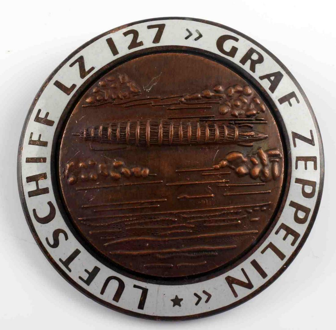 WWII GERMAN GRAF ZEPPELIN AIR SHIP LZ 127 BADGE: German World War II Graf Zeppelin LZ 127 Air Ship Badge. Measures 1 3/4" inches diameter. The front reads ‘Luftschiff LZ 127 Graf Zeppelin’. The front shows the Zeppelin flying over water. The rev