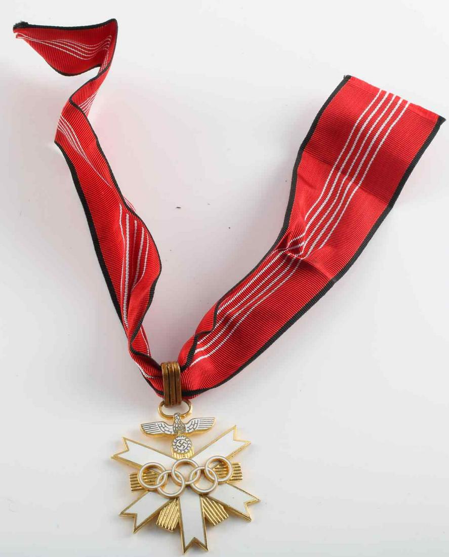 WWII THIRD REICH OLYMPICS 1ST CLASS NECK ORDER: German WWII 1936 Berlin Olympics 1st Class Neck Order. Measures 2 1/4” wide by 2 9/16” tall. The front shows the five Olympic rings in the center of a five armed cross with rays in the back ground
