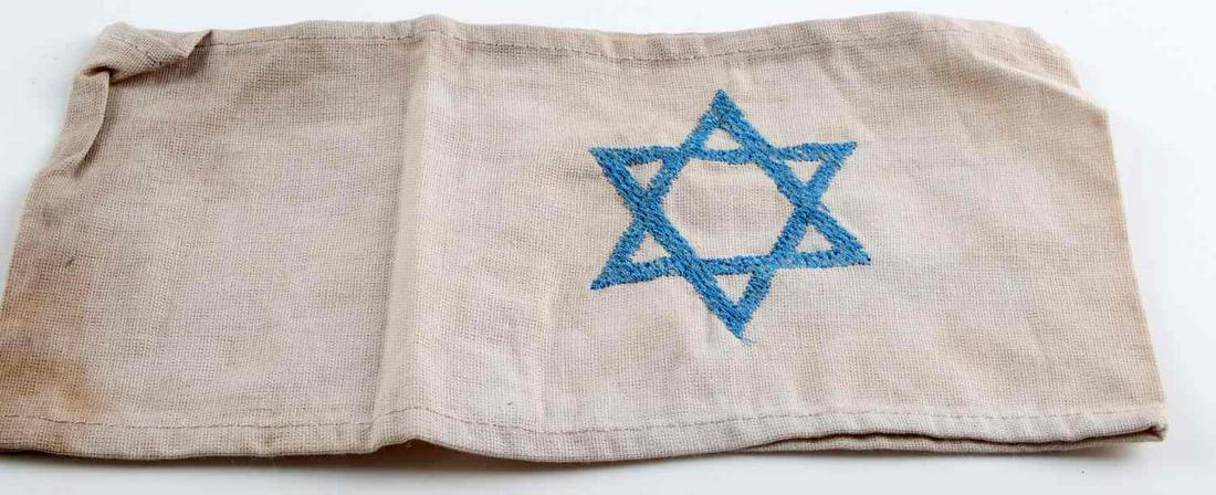 WWII THIRD REICH JEWISH CONCENTRATION CAMP ARMBAND: German WWII Jewish Star Concentration Camp Arm Band. Measures 8 3/4” wide by 4 1/4” tall. The front shows a blue Jewish star in the center. One piece machine sewn and machine embroidered cotton co