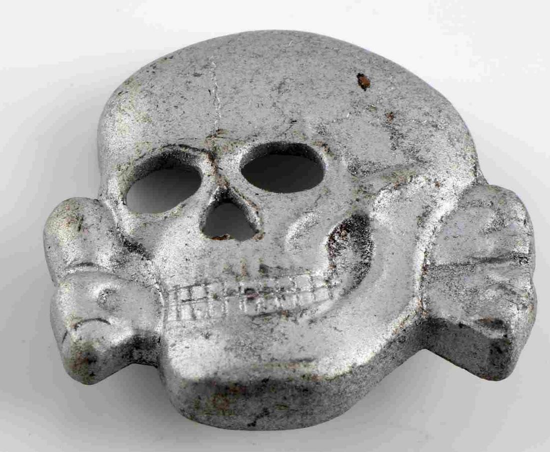 WWII GERMAN THIRD REICH SS TOTENKOPF VISOR PIN: German WWII Waffen SS Schutz Staffel Officers Visor Cap Skull. Measures 1 3/16 x 1 1/8 tall. The front shows the version with the skull that has the lower jaw. The reverse side is maker marked ‘RZM