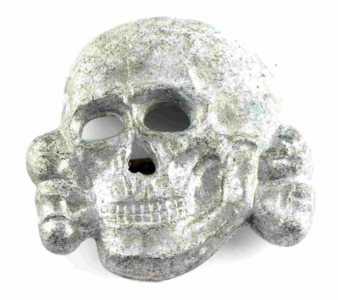 WWII GERMAN THIRD REICH SS TOTENKOPF VISOR PIN: German WWII Waffen SS Officers Visor Cap Skull. Measures 1 1/4 X 1 1/8 inches. The front shows a Waffen SS skull and cross bones with the jaw. The reverse side is maker marked ‘RZM M1/24’. Has two