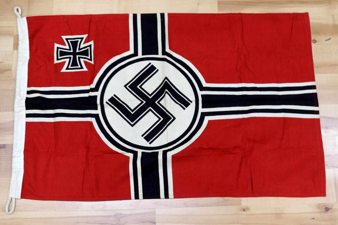 WWII GERMAN WAFFEN SS SWASTIKA BATTLE FLAG: Measures 35 X 21 1/8 inches. Swastika in the center with an Iron Cross in the corner. White cotton bunting with rope on one end that is maker marked ‘REICHSKREIGSFAHNE KLEIN & FOST KG BERLIN 86 X 55