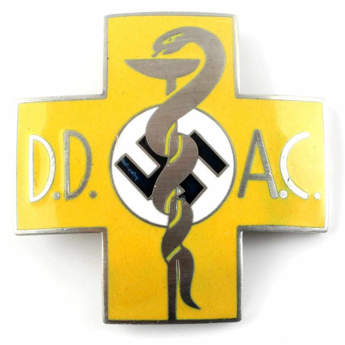 WWII GERMAN MEDICAL DOCTOR DD AC BREAST BADGE: WWII German Medical DD AC Doctors Breast Badge. Measures 1 7/8 inches wide by 1 7/8 inches tall. The front shows a snake wrapped around a beaker. It reads ‘DD AC’. The reverse side is maker marked
