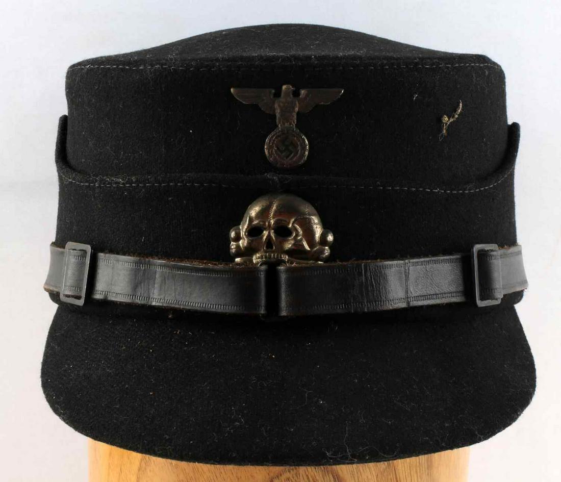 WWII GERMAN THIRD REICH SS KEPI FOR ENLISTED MAN: Third Reich SS Kepi for an enlisted man. Features a type 1 totenkopf pin and Parteiadler pin. Size 57. SS stamped on interior. Tag underneath leather liner reads "dam Reichsfurher SS Asfuhrung RZM." D