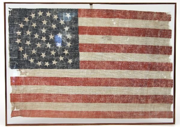 38 STAR UNITED STATES FLAG: Printed Linen 38 star American Flag, c.1877, 18 x 12.5 inches. Framed in glass. Some toning, stains minor moth. The 38-Star Flag: This Flag became the Official United States Flag on July 4th, 1877. A 