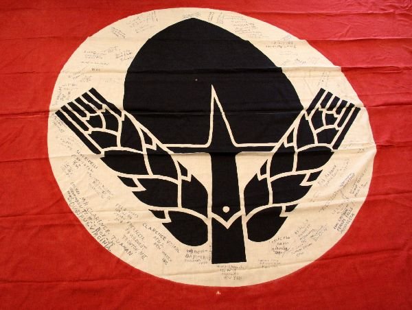 CAPTURED & SIGNED GERMAN WWII RAD LABOR FLAG: A large printed linen measuring 151 x 88 inches with metal hang loops. Flag features the agency's symbol of a black shovel spade with barley on a red field. Ink signatures are clearly visible. Some li