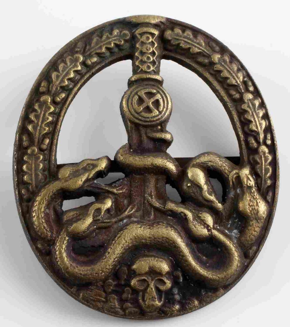 WWII GERMAN ANTI PARTISAN WARFARE BADGE: WWII German Anti-Partisan warfare badge. Obverse features sword to center with swastika with four snakes below above a skull with an oak leaf wreath. Flat horizontal pin. 2 1/4 X 2 inches. Unauthentic