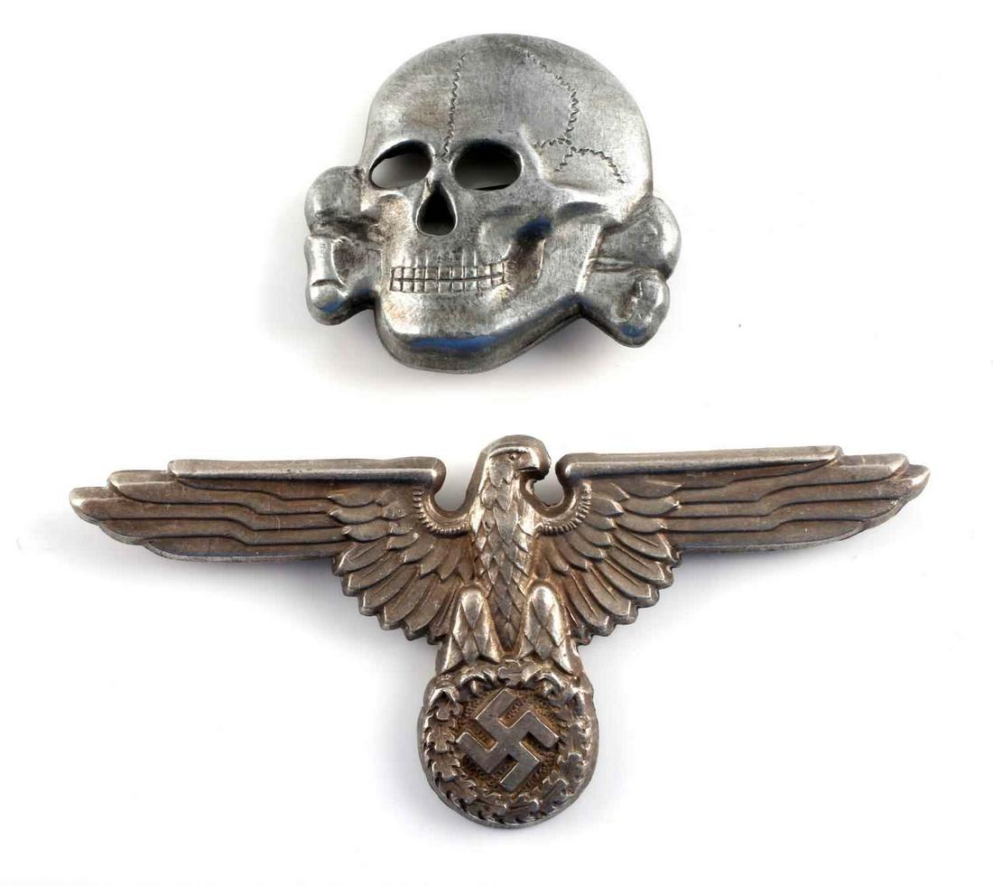 2 WWII GERMAN WAFFEN SS VISOR CAP EAGLE AND SKULL: Both are maker marked ‘RZM M1/24’ on the reverse side. They have two flat horizontal prongs on the back. Stamped nickel construction. Eagle measures 3 X 1 1/2 inches and totenkopf measures 1 1/2 X