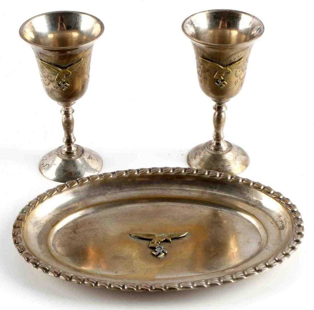 WWII GERMAN LUFTWAFFE PILOT TRAY AND SCHNAPPS CUPS: WWII German Luftwaffe Pilot's tray and schnapps cups. All pieces have the Luftwaffe eagle. Tray marked "E.P.N.S.". Tray measures 6 1/2 X 4 1/2 inches. Schnapps cups measure 3 3/4 inches. All in good c