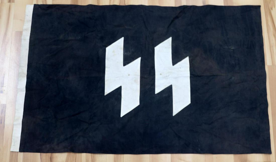 WWII GERMAN REICH SS BLACK HAUSFAHNE HOUSE FLAG: WWII German Reich SS black "Hausfahne" house flag measuring 46 1/2 inches wide by 24 1/2 inches tall. Flag is in good overall condition, with intermittent staining, and blemishing. Does not fluoresce.