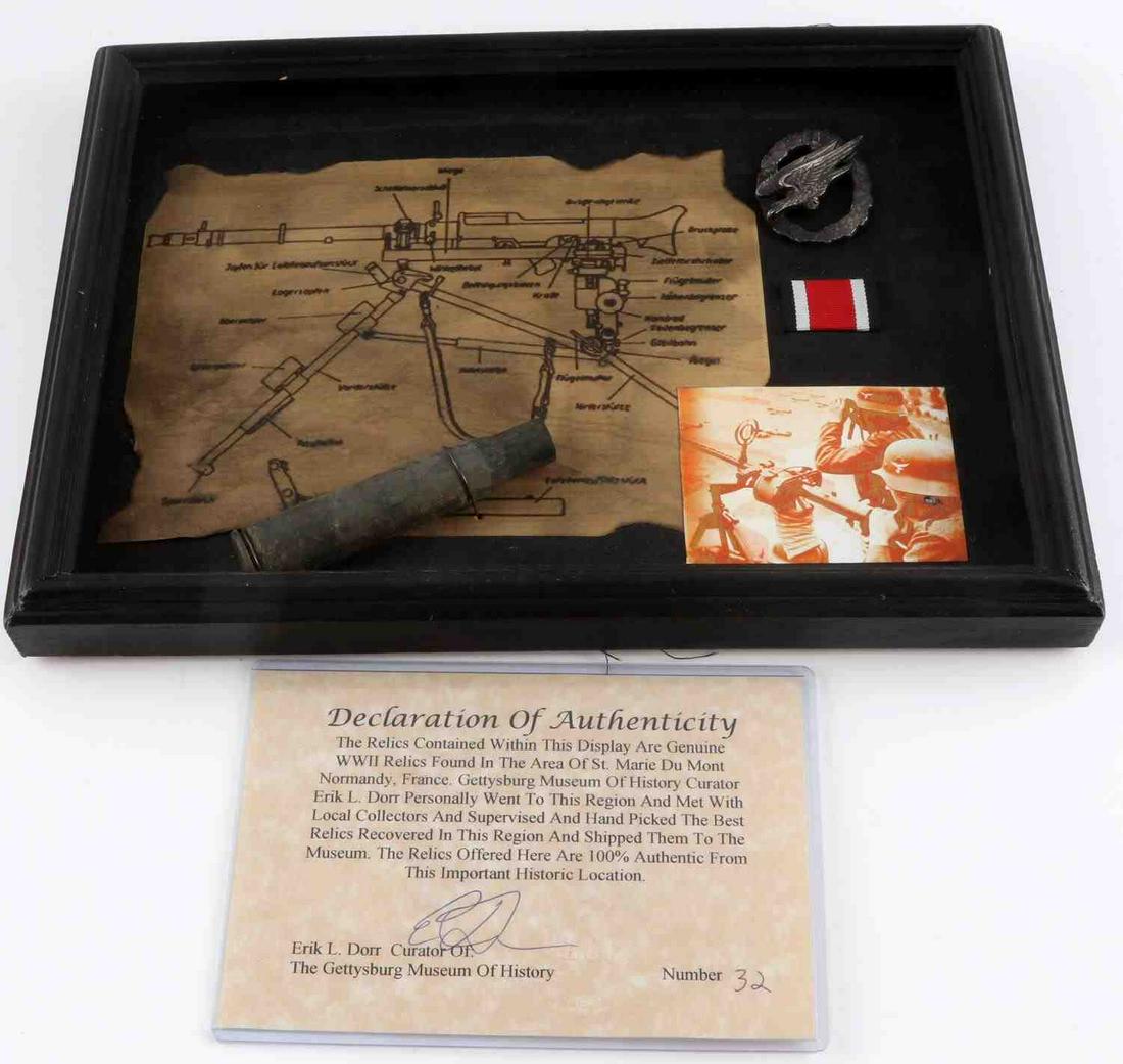 WWII GERMAN PARATROOPER BADGE & MG42 SPEC CASE: Framed display includes: Paratrooper badge (missing pin at rear), MG42 spec sheet in German, 3.5 X 2.5 inch photo of German soldiers with gun, small ribbon, and a .50 caliber shell case. COA included.
