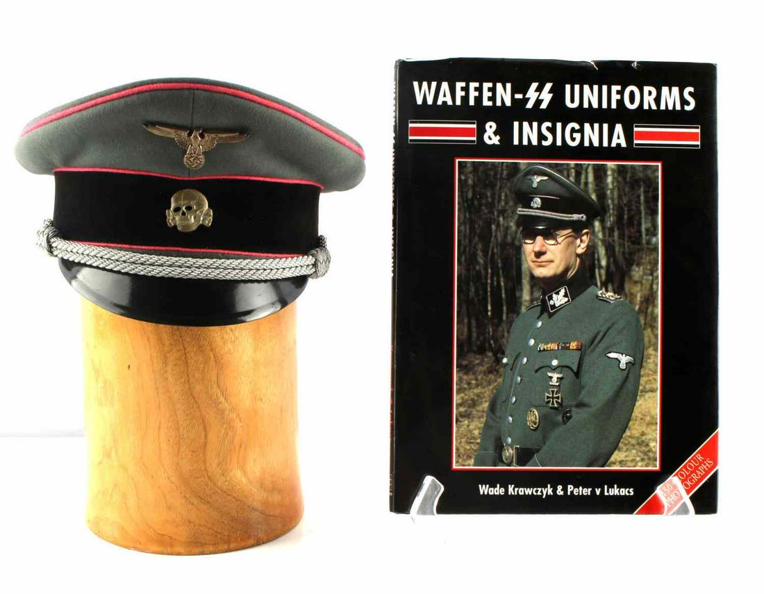 WWII GERMAN PANZER TANK VISOR CAP AND BOOK: WWII German Panzer Tank visor cap with book. Green cloth visor with pink piping featuring the eagle and totenkopf to the front with a twisted silver chin cord. Black felt strap around the cap. beige s