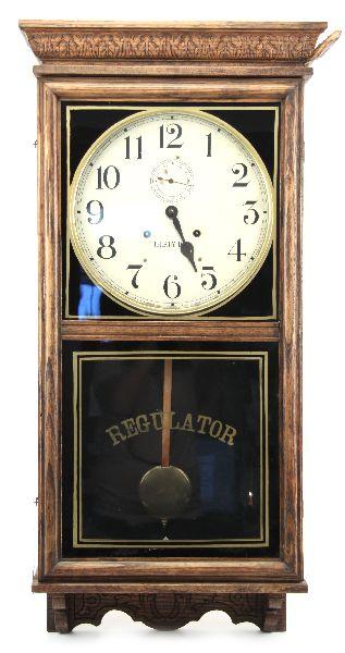 WATERBURY STORK STORE REGULATOR WALL CLOCK: 36x16x4.5 inches. Early 20th century oak case Waterbury thirty day regulator clock with 11 inch paper dial. Label on back is complete. Clock is in good condition with minute hand absent and loose pane