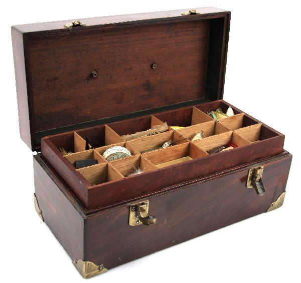 VINTAGE WOODEN TACKLE BOX WITH LURES REELS EXTRAS: 18x9x 7 inches. Vintage mahogany box with leather handle, brass hardware and bottom corner reinforcements. Piano lid hinge. Box bottom contains a Shakespeare "Triumph" reel in excellent condition, man