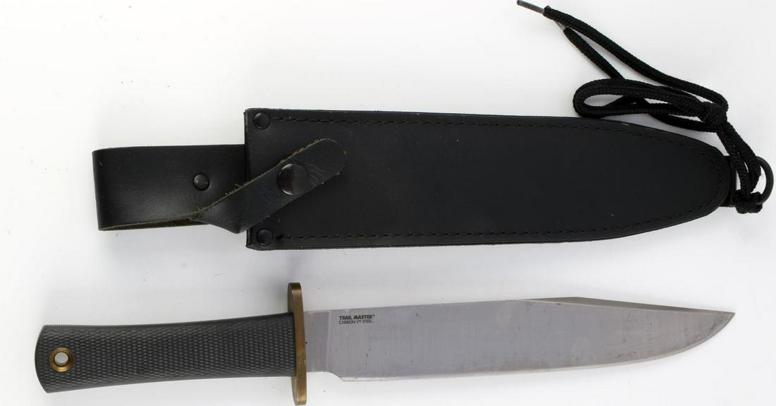 COLD STEEL TRAIL MASTER BOWIE KNIFE W SCABBARD: A Cold Steel Trail Master Bowie knife. Carbon 5 stainless steel blade with brass crossguard and leather grip. Measures 14 1/2 inches. Made in USA. Good condition.