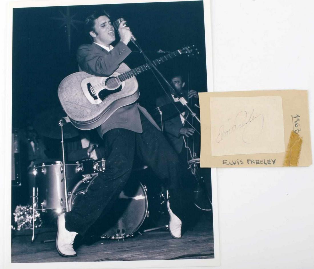 1963 ELVIS PRESLEY CUT AUTOGRAPH AND PHOTOGRAPH: Lot features a cut autograph from Elvis Presley. Measures 2 3/3 inches. Deemed authentic according to terms. The photograph is of Elvis performing on stage with his signature hand tooled leather cover