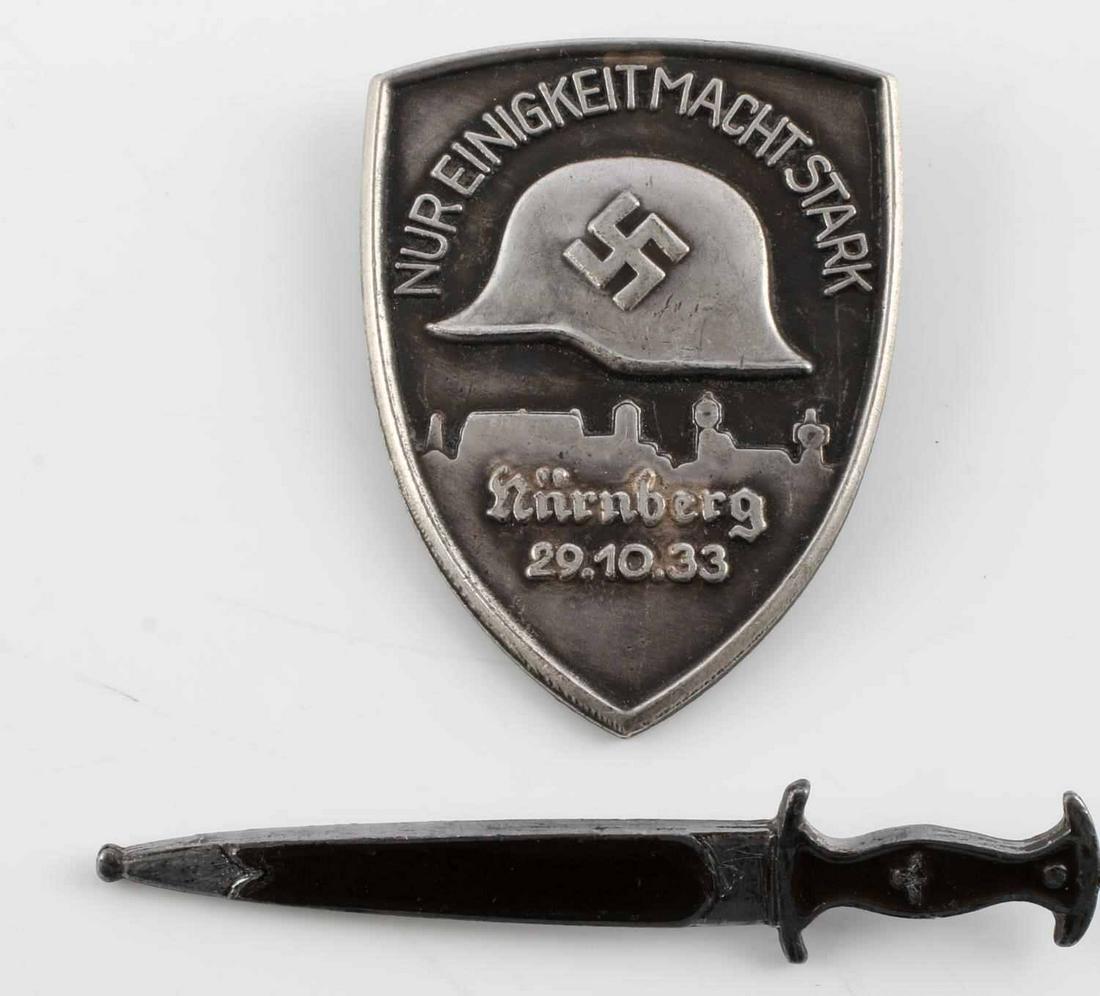 WWII GERMAN THIRD REICH LOT OF 2 PINS NURNBERG: 1 Shield shaped Nureingkeit macht stark Nurnberg 29.10.33 pin. 1.75 inches by 1.25 inches. 1 Dagger straight pin 2.25 inches long. enamel on blade and handle. Unauthenitcated sold as is.