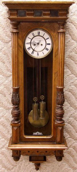 GERMAN WALNUT CARVED CASE REGULATOR WALL CLOCK: late 19th century Long case wall clock with enameled face. Roman numerals. Front and side glass intact. Walnut case features fluted columns adorned with acacia leaves and dentil molding on top. Overal