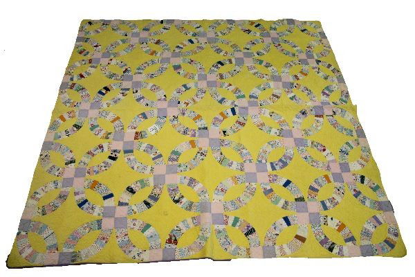 EARLY 20TH C. AMERICAN DOUBLE WEDDING RING QUILT: Circa 1930's. 82x84 inches double wedding ring pattern on a yellow background with purple piping and backing. Very good condition.