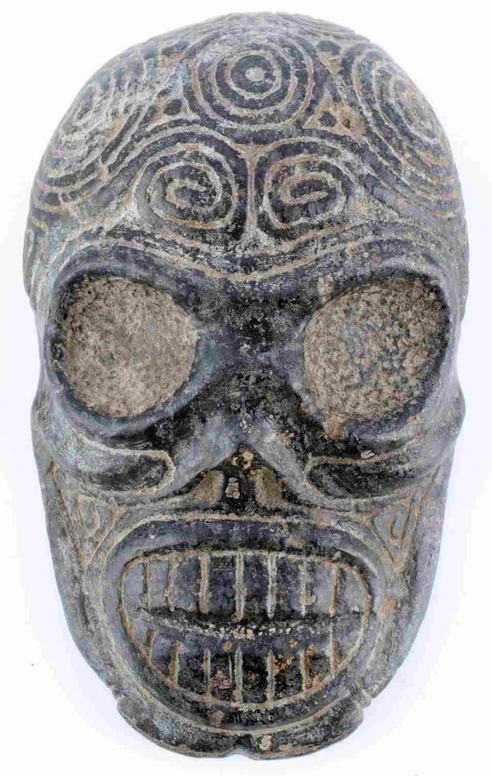 PRE COLUMBIAN TAINO COMPLEX DESIGNED SKELETAL HEAD: Taino skeletal head with complex mix of bird head symbols on forehead and back of skull. Well defined eye and mouth surround, a typical Taino design feature. Teeth are slightly parted. Residual arms s